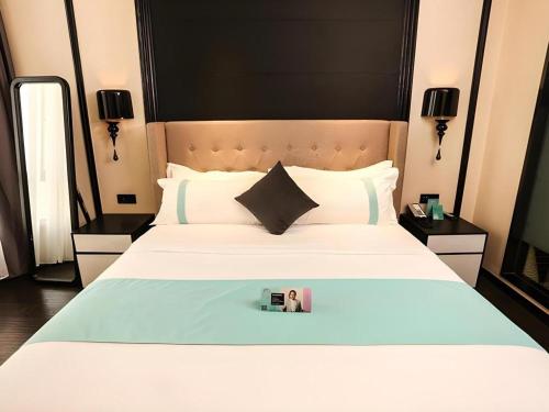 a bedroom with a large white bed with a picture on it at Xana Hotelle·Ji'nan Hi-tech Zone Century Avenue Tangye in Jinan