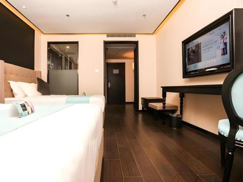 a hotel room with a bed and a flat screen tv at Xana Hotelle·Ji'nan Hi-tech Zone Century Avenue Tangye in Jinan