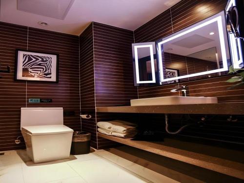 a bathroom with a toilet and a sink and a mirror at Xana Hotelle·Ji'nan Hi-tech Zone Century Avenue Tangye in Jinan