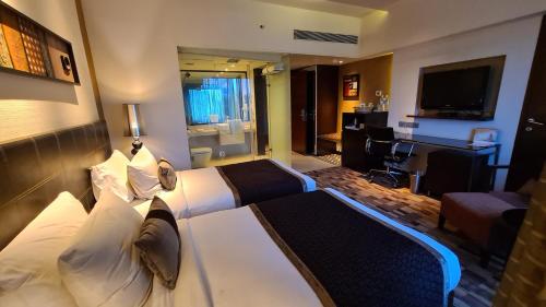 a hotel room with a bed and a living room at Pride Hotel Pune in Pune