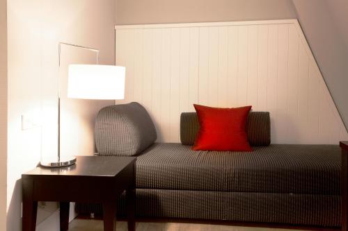 a red pillow sitting on a couch next to a lamp at Hotel Victoria in Frankfurt/Main