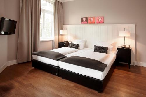 a bedroom with a large bed with two lamps and a television at Hotel Victoria in Frankfurt/Main