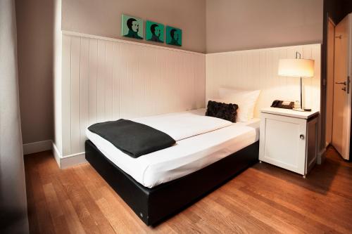 a bedroom with a bed with a black blanket on it at Hotel Victoria in Frankfurt/Main