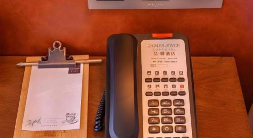 a calculator sitting on a table next to a clipboard at James Joyce Coffetel Wuhan Gutian Er Road Metro Station in Wuhan