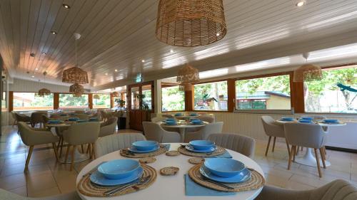 a restaurant with tables and chairs and blue dishes on them at Balaton Colors Beach Hotel in Siófok