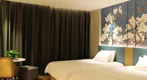 a bedroom with two beds and a painting on the wall at Magnotel Wulanhaote Hanshan Dong Street in Ulan Hot