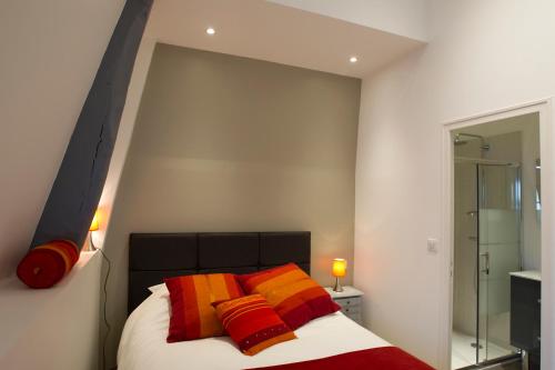 トゥールにあるGit'Appart au bord de Loireのベッドルーム1室(オレンジと黄色の枕が付いたベッド1台付)