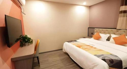 a bedroom with a bed and a desk with a tv at Shell Hotel Shanghai Jinshan Wanda Plaza in Nanhui