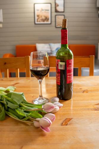 a bottle of wine and tulips on a table with a glass at Domki Primore in Władysławowo