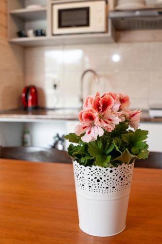 a white vase with pink flowers sitting on a table at Domki Primore in Władysławowo
