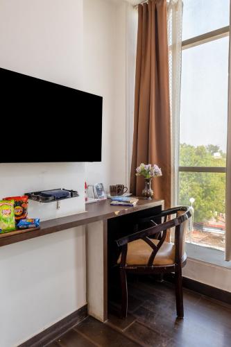 a room with a desk with a television and a chair at Hotel Tashree Near T3 - Free Airport Drop in New Delhi