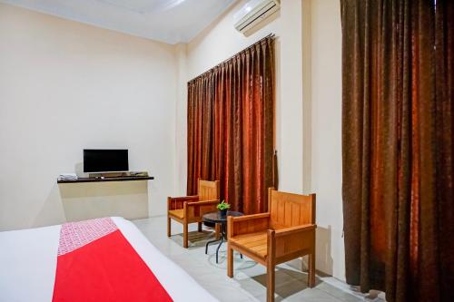 a bedroom with a bed and two chairs and a television at OYO 94680 Ralica Residence in Medan