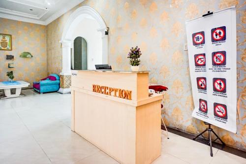 a reception desk in a room with a happy hour sign on the wall at OYO 94680 Ralica Residence in Medan