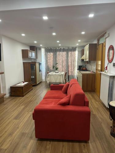 ein Wohnzimmer mit einem roten Sofa und einer Küche in der Unterkunft la Casa sul Corso -- alloggio turistico -- appartamento open space in Torricella Peligna