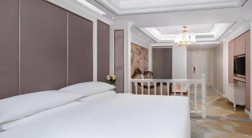 a white bedroom with a large bed and a chandelier at Vienna Hotel Guangdong Shantou South Bus Station in Shantou