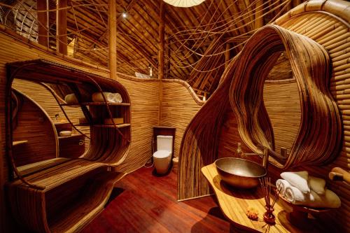 a room with a wooden room with a bed and a desk at Hideout Eco Bamboo House Bali in Selat