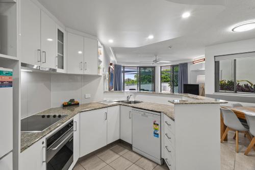 a kitchen with white cabinets and a table and chairs at Malibu Apartments in Mooloolaba