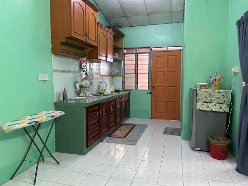 cocina con paredes verdes y puerta roja en Anuarosi Homestay Taman Melor, Teluk Intan, en Teluk Intan