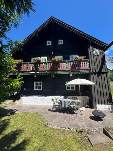 a house with a table and an umbrella in front of it at Knollhäusl in Ramsau am Dachstein