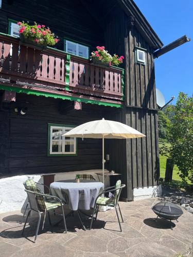 a table with an umbrella in front of a building at Knollhäusl in Ramsau am Dachstein
