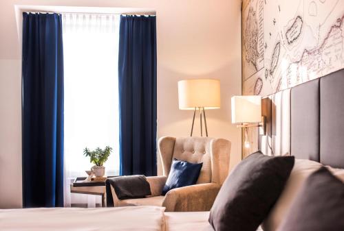 a bedroom with a bed and a chair and a window at Hotel Novum in Hinte