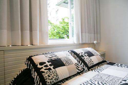 uma cama num quarto com uma janela em Charmoso Flat em Ipanema no Rio de Janeiro