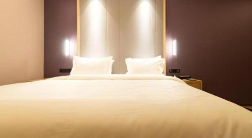 a large white bed with two pillows on it at Lavande Hotel Changchun Gaoxin Jilin University in Changchun