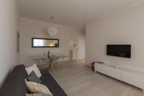 sala de estar con sofá y TV en la pared en St. Vitale’s Basilic view elegant apartment, en Rávena