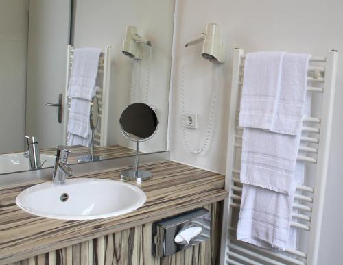 a bathroom with a sink and a mirror and towels at Hotel Tannhäuser in Heidelberg