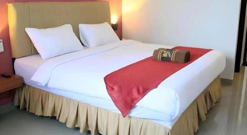 a large white bed with a bag sitting on it at Garuda Hotel Pontianak in Pontianak