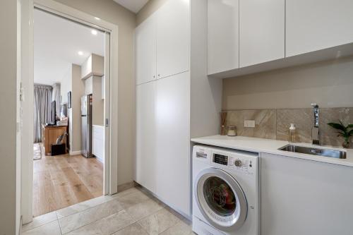 a kitchen with a washing machine in a white kitchen at Great Ocean Road Sunrises in Lorne