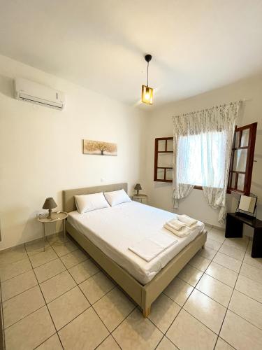 a bedroom with a white bed and a window at Anemoessa in Ammoudia