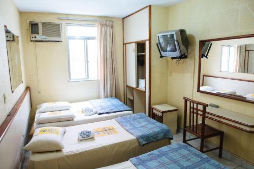 a hotel room with two beds and a tv at Hotel Caxambu in Rio de Janeiro