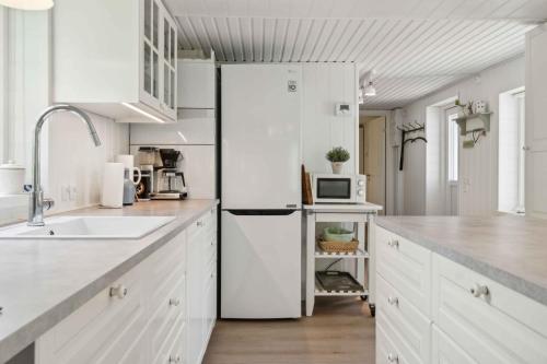 a kitchen with white cabinets and a white refrigerator at Lovely Summer House Close To Stillinge Beach in Slagelse