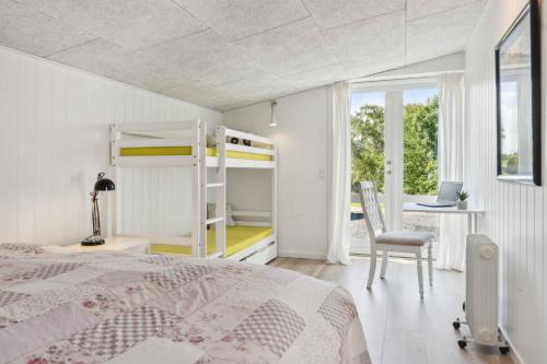 a bedroom with a bunk bed and a desk with a laptop at Lovely Summer House Close To Stillinge Beach in Slagelse