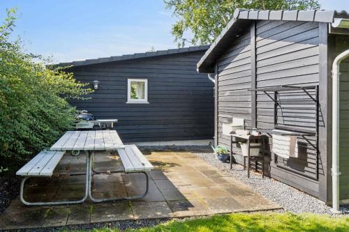 a picnic table in front of a black building at Lovely Summer House Close To Stillinge Beach in Slagelse