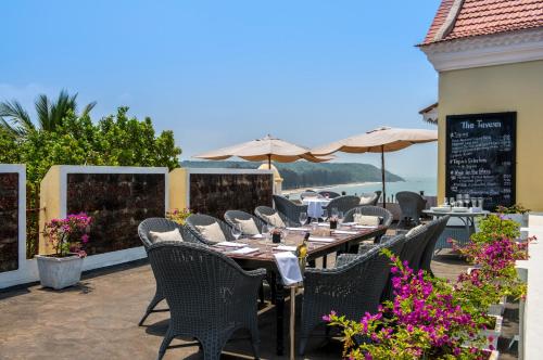 a table with chairs and umbrellas on a patio at Fort Tiracol Goa in Arambol