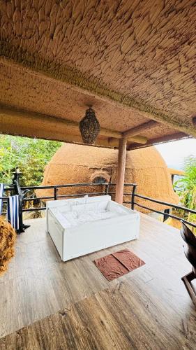 a white table on a wooden floor with a thatched roof at Dream Cliff Mountain Resort in Haputale