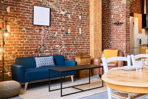 - un salon avec un canapé bleu et un mur en briques dans l'établissement Appartement 2 chambres atypique en souplex, à Lille