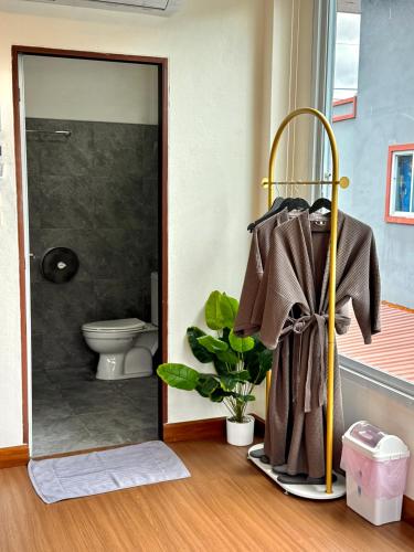 a bathroom with a toilet and a robe on a rack at khaosok Center Guesthouse in Khao Sok National Park