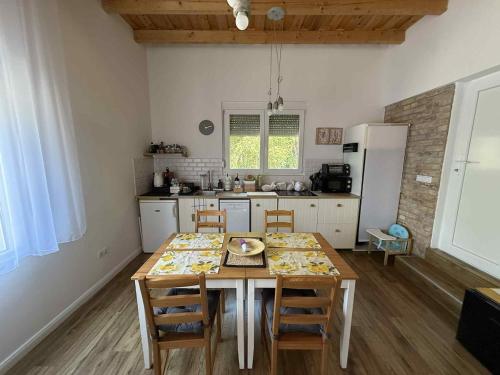 a kitchen with a wooden table with chairs and a refrigerator at Vörös Patak Apartmanház -Red Creek Apartmant House in Balatonfůzfő