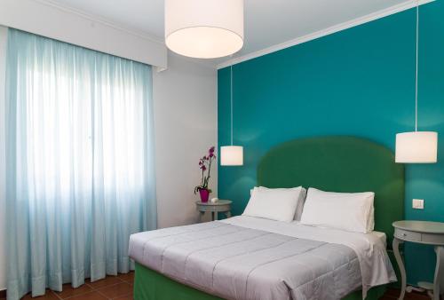 
a bedroom with a white bed and a blue wall at Keri Village & Spa by Zante Plaza (Adults Only) in Keri
