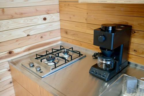 a kitchen counter with a stove and a coffee maker at 衣食住が楽しめるデザイナーズホテル E-YADO 新潟 Niigata in Niigata