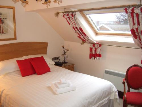 a bedroom with a bed with red pillows and a window at Moss Lodge in Rochdale