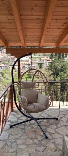 a hanging chair on a porch with a wooden roof at family home in Dhimitsana