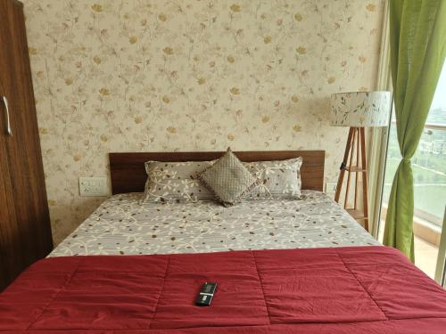 a bed with a red blanket and a remote control on it at Staeg Night Sky View 2BHK - 1605 in Indore