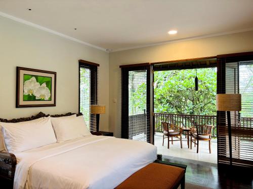 a bedroom with a bed and a balcony at Bumi Kinar Heritage in Ubud