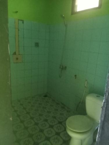a bathroom with a toilet and a tiled floor at Bukit Senaru Homestay in Senaru