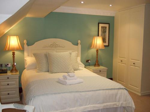 a bedroom with a white bed with two lamps at Moss Lodge in Rochdale
