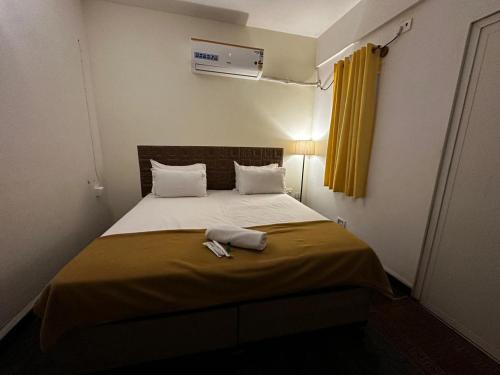 Dormitorio pequeño con cama con cortina amarilla en MPS Sai Palace, en Tiruvannāmalai